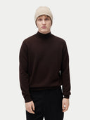 Model trägt die gerippte Mütze in Warmes Gray zu einem dunkelbraunen Stehkragenpullover