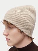 Seitenansicht der Rippenstrickmütze in Warmes Gray mit breitem Umschlag am Kopf eines Models