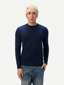 Model trägt beige Rippstrickmütze zu dunkelblauem Pullover und Jeans, Ganzkörperansicht von vorn