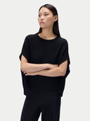 Model in schwarzem Oversize-Oberteil, Nahansicht von vorn mit verschränkten Armen