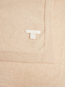 Detailaufnahme der beigen Decke mit eingenähtem Label und Strickkante