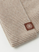 Detailansicht des Rippenstricks in Warmes Gray mit braunem Etikett mit Ornamentlogo am Umschlag