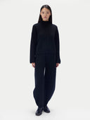 Modell trägt schwarze Damen Kaschmir Strickhose mit Tonnenbein und passenden Stehkragenpullover, Vorderansicht