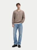 Model in taupefarbenem Pullover und hellblauer Jeans, Ganzkörperansicht von vorn