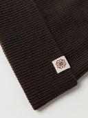 Detailaufnahme des Rippenstrick-Umschlags in Olive Brown mit aufgenähtem Logo-Etikett