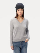 Model mit Kaschmir Strickmütze in Midnight Blue, grauem Pullover mit V-Ausschnitt und Jeans, Ganzkörperansicht von vorne