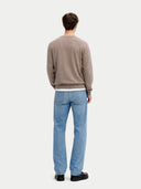 Rückansicht des taupefarbenen Pullovers am Model, kombiniert mit Jeans und schwarzen Schuhen
