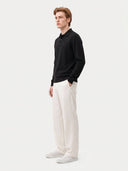 Seitenansicht des schwarzen Polostrickpullovers mit langen Ärmeln und Rippbündchen am Model