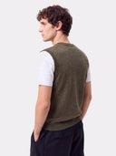 Model von hinten in olivgrüner Strickweste über weißem T-Shirt und schwarzer Hose
