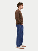Seitenansicht des Pullovers in Dark Brown, am Model mit blauer Jeans und hellen Sneakern