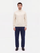 Model trägt weißen Kaschmirpullover zu dunkler Jeans und Loafern, Ganzkörperansicht von vorn