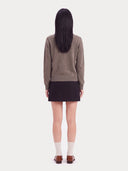 Rückansicht des taupefarbenen Strickpullovers am Model mit schmalem Rippbund