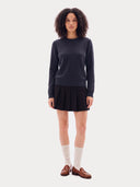 Frontansicht am Model: Navy Strickpullover zu schwarzem Faltenrock und braunen Loafern