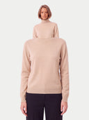Nahaufnahme des beigen Pullovers am Modell, hoher Kragen und glatter Jersey-Strick