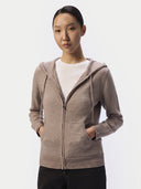 Model trägt den Damen Kaschmir Zip-Hoodie in Taupe offen über weißem Shirt, Hände in den Smiley-Taschen, Vorderansicht