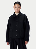 Modell trägt die schwarze Jacke geschlossen, Nahaufnahme von Kragen und Knopfleiste