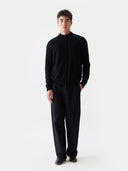 Model trägt die schwarze Strickjacke mit geschlossenem Reißverschluss zu dunkler Hose, Ganzkörperansicht von vorne