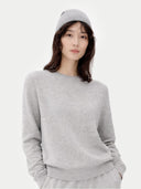 Model trägt den hellgrauen Rundhals-Pullover mit passender Mütze, Nahaufnahme von vorne