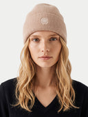 Modell trägt beige Rippmütze mit breitem Umschlag und gesticktem Emblem, Nahaufnahme von vorn