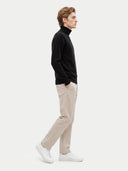 Seitenansicht am Modell, schwarzer Pullover in leichter Form über beiger Hose