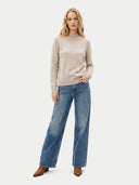 Model trägt den Strick in natural beige zu weiter Jeans, Ganzkörperansicht von vorne