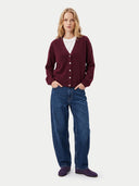 Frontansicht am Model: weinrote Strickjacke mit V-Ausschnitt über weißem Top zu blauer Jeans