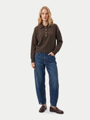 Frontansicht am Model: dunkelbrauner Polopullover mit Knopfleiste zu blauer Jeans und braunen Lederloafern