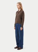 Seitenansicht am Model: dunkelbrauner Polopullover zu weiter blauer Jeans und braunen Lederschuhen