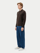 Seitenansicht des Strickpolos in Olive Brown mit langen Ärmeln, zu weiter Jeans kombiniert
