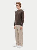 Seitliche Ansicht des braunen Pullovers mit glattem Jersey-Strick, kombiniert mit heller Hose