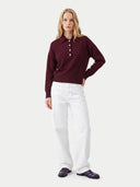 Frontansicht am Model: weinroter Polopullover aus Kaschmir zu weißer Hose und dunklen Loafern