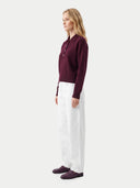 Seitenansicht am Model: weinroter Polopullover zu weißer weiter Hose und dunkelroten Loafern