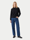 Model trägt schwarzes Kaschmiroberteil zu blauer Jeans und Loafern, Vorderansicht
